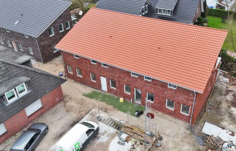 Luftaufnahme eines neuen Wohnhauses mit rotem Ziegeldach in Ocholt