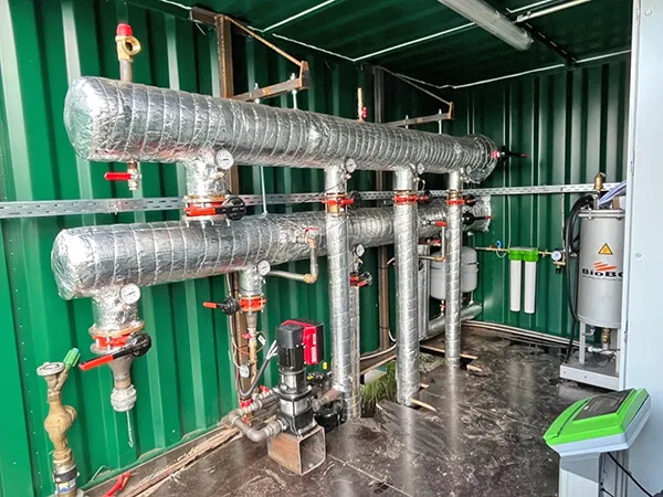 Gedämmte Heizungsverteilung mit Pumpen und Armaturen im Container