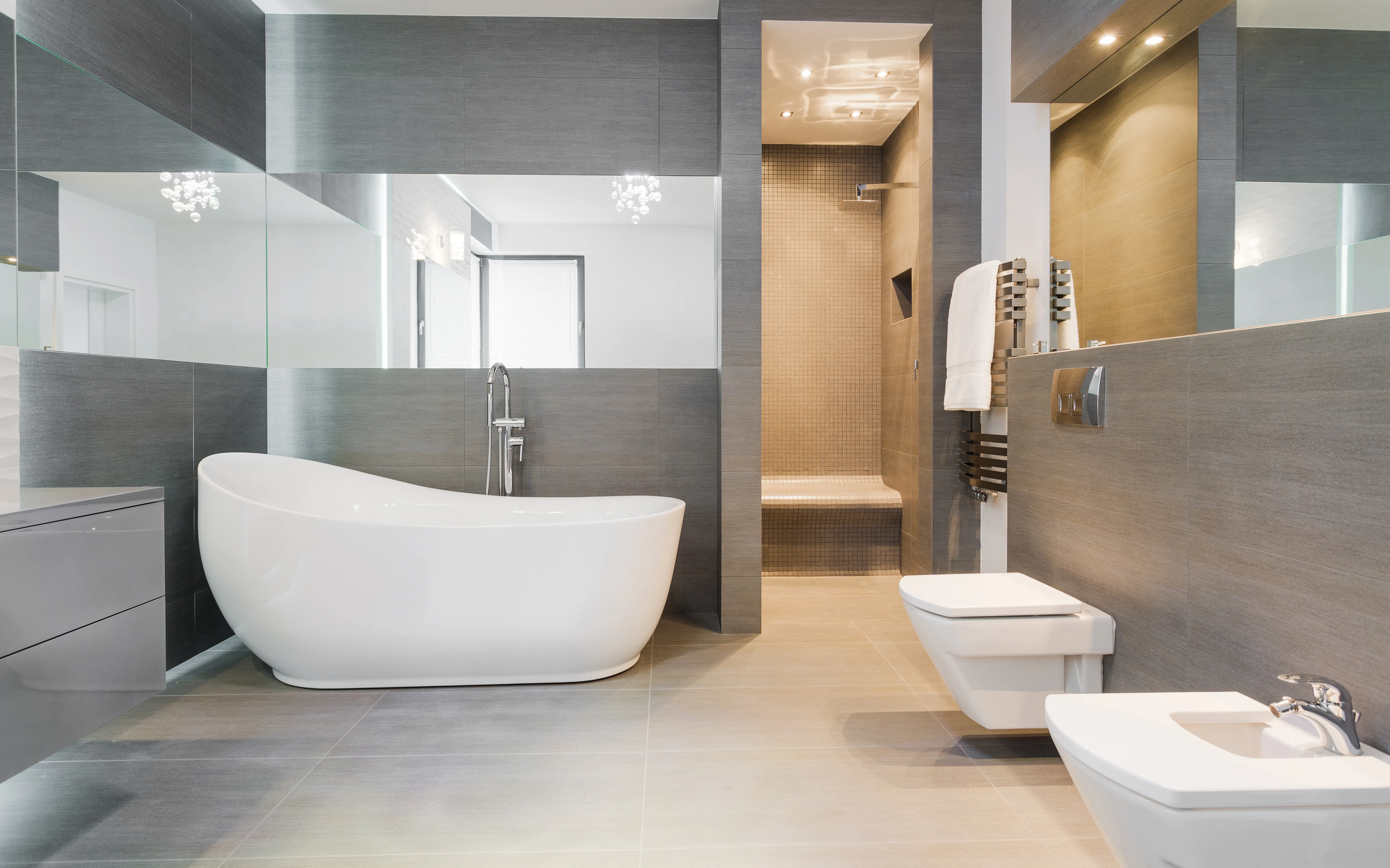Badezimmer mit freistehender Badewanne, wandhängendem WC und Bidet